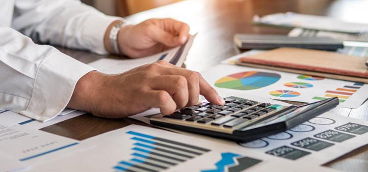 Person Running Calculations on Paper with Calculator